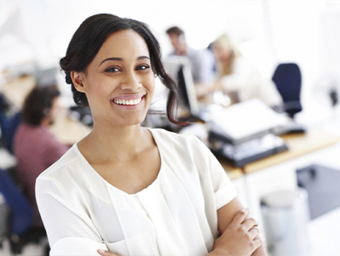 Businesswoman standing in office with co-workers in background